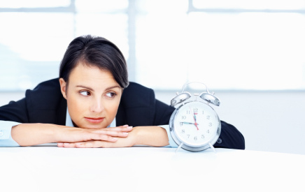 A relaxed beautiful middle aged woman looking at alarm clock on desk